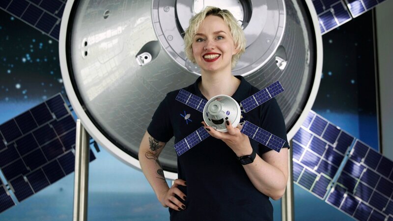 Raumfahrtingenieurin Annemarie Lohse vor einem Modell des Orion-Raumschiffs. Bei Airbus in Bremen wird das Europäische Service Modul (ESM) gefertigt. – Bild: ZDF und MDR/​Tellux/​Dirk Lütter
