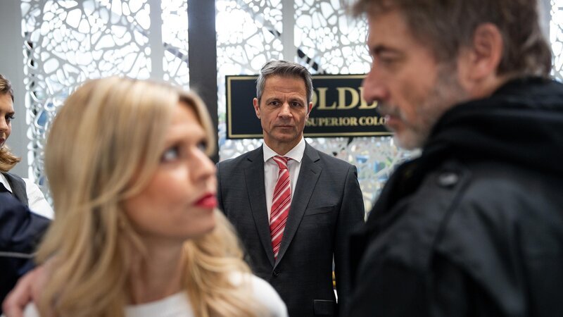 Benedikt (Jens Hajek, M.) registriert beunruhigt einen nahen Moment zwischen Patrizia (Miriam Lahnstein) und ihrer Familie. Rechts Jori (Guido Broscheit). – Bild: RTL /​ Jule Zielke