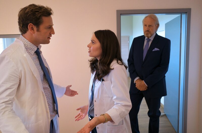 Eifersucht: Dr. Timotheus von Hatzfeld (Tom Radisch, l.) und Dr. Carolin Thelen (Diane Willems, M.) streiten sich, als plötzlich Timos Vater Alexander von Hatzfeld (Reiner Schöne, r.) in der Praxis auftaucht. – Bild: ARD/​Jacqueline Krause-Burberg