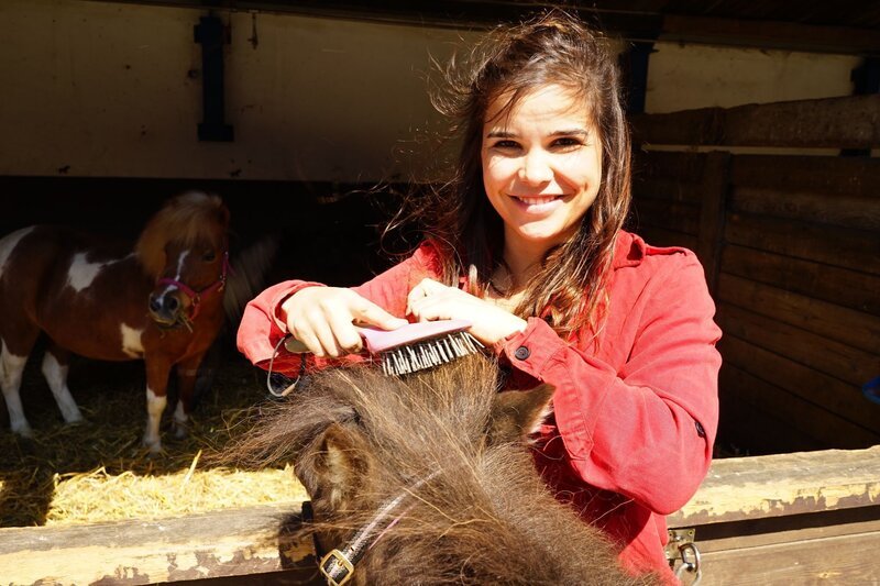 Anna lernt, wie man das dichte Fell und die volle Mähne der Ponys richtig pflegt. – Bild: BR/​Text und Bild Medienproduktion GmbH & Co.KG/​Franziska Gruber