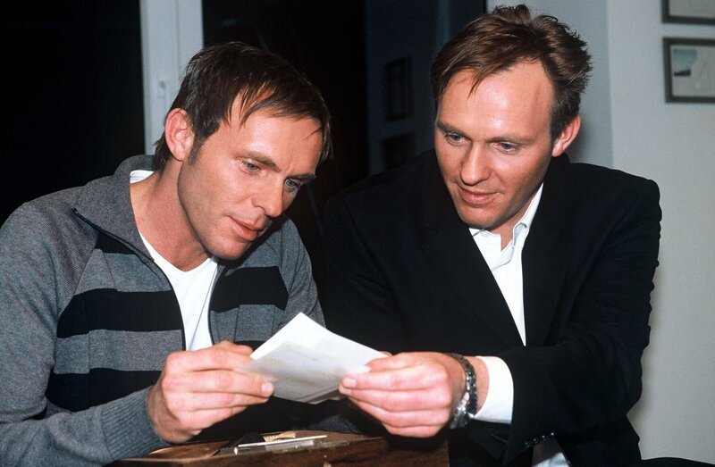 Falk (Dirk Martens, l.) und sein Zwillingsbruder Harro (Uwe Martens, r.) stöbern in alten Familienfotos. – Bild: SAT.1 /​ Münstermann