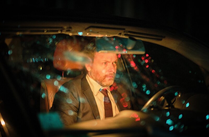 Irgendetwas hat hinter dem Wagen gepoltert … aber Ben Dellien (Nicholas Reinke) hat es eilig. – Bild: SWR/​Benoît Linder