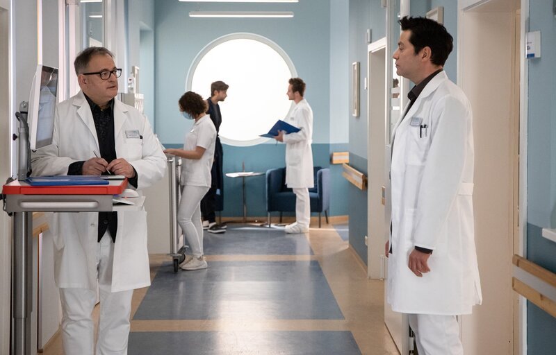 Hans-Peter Brenner (Michael Trischan, li.) fragt Dr. Philipp Brentano (Thomas Koch, re.), was ihm für eine Laus über die Leber gelaufen ist, den ganzen Tag schon blafft er seine Kollegen an. Philipp erzählt Hans-Peter von dem morgendlichen Streit mit seinem kleinen Sohn Max und dessen Bemerkung, dass er ja sowieso nicht sein richtiger Vater sei. – Bild: MDR/​Saxonia Media/​Rudolf Wernicke