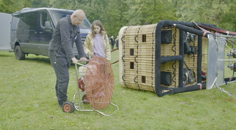 Die Vorbereitungen für die Ballonfahrt laufen. Ein Riesenventilator bläst Luft in den Ballon. – Bild: rbb/​Pangolin Doxx