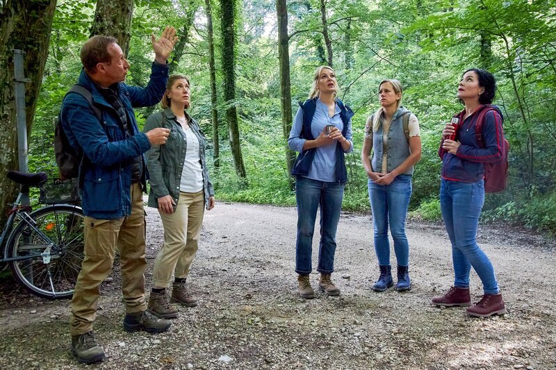 Walter Rübesam (Mike Maas, l.), Steffi Kurtz (Ines Honsel, 2.v.l.), Judith Färber (Nina Brandhoff, M.) und Rosi Mitterer (Simona Mai, 2.v.r.) vom Verein der „Rosenheimer Waldfreunde“ erklären Frau Stockl (Marisa Burger, r.), was beim „Waldbaden“ zu beachten ist. – Bild: ZDF /​ ORF /​ Bojan Ritan