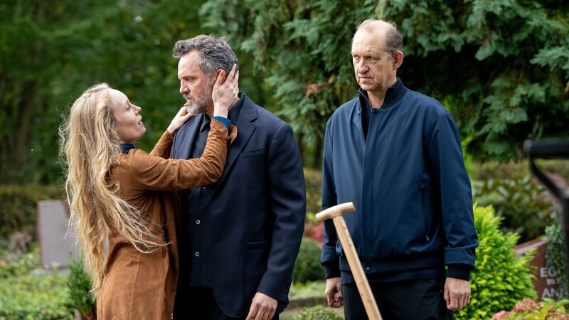 Kommissar Carl Sievers (Peter Heinrich Brix, r.) führt das Ehepaar Winka Vetter (Katharina Heyer, l.) und Tom Soest (Roland Silbernagl, M.) auf den Friedhof vor ein leeres Grab. Hier sollte eigentlich Winkas verstorbener erster Mann liegen – aber der Sarg ist leer. – Bild: ZDF und Georges Pauly