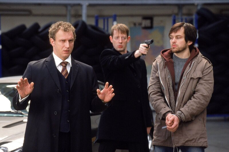 König (Matthias Komm, li.) hat Carstens Bruder Robert (Ole Puppe, re.) als Geisel genommen, er will von Carsten die Unterlagen. Doch Carsten hat sich seinerseits eine Waffe besorgt und zielt auf König … (Mi. Luc Feit) – Bild: RTL /​ Guido Engels /​ Außer Kontrolle