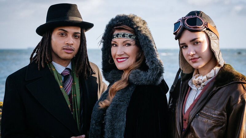 Freuen sich zu früh auf ein entspanntes Krimi-Wochenende in einem Inselhotel: Fergus (Rohan Nedd), Harry Wild (Jane Seymour, M.) und ihre Enkelin Lola (Rose O’Neill). – Bild: Szymon Lazewski