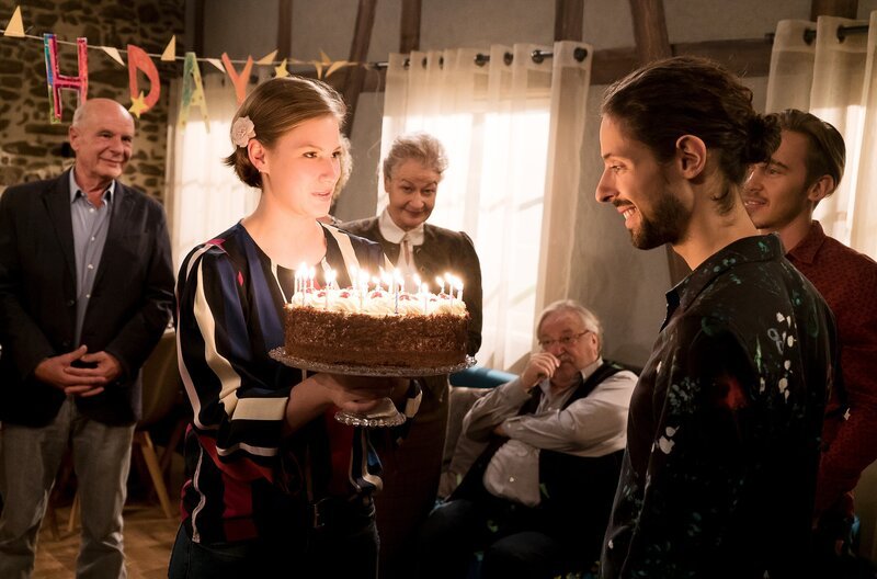 Im Gesindehaus steigt eine Riesengeburtagsparty für Albert (Alessio Hirschkorn, re.) und Celine (Ana-Carolina Kleine) überreicht die Geburtstagstorte. – Bild: SWR/​Stephanie Schweigert