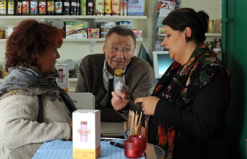 Die Landfrauen wissen nicht so recht, was sie von den LED betriebenen Grablichtern halten sollen. Von links: Landfrau Gundi (Helga Januschkowetz), Alois Preissinger (Erich Hallhuber) und Monika Vogl (Christine Reimer). – Bild: BR/​Marco Orlando Pichler
