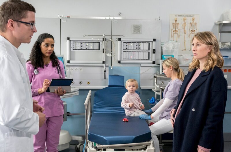 Dr. Elias Bähr (Stefan Ruppe, l.) betreut mit Dr. Emma Jahn (Elisa Agbaglah, 2.v.l.) die hochschwangere Tanja Jakobs (Gabriela Lindl, r.), deren eineinhalb-jährige Tochter Lotte operiert werden muss (mit Komparsin). – Bild: ARD/​Jens Ulrich Koch
