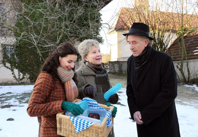 Hildegard (Antje Hagen, M.) und Elena (Lili Gesler, l.) versuchen, Pfarrer Fröhlich (Viktor Schenkel, r.) mit einem Schweinebraten zu versöhnen. – Bild: ARD/​Ann Paur