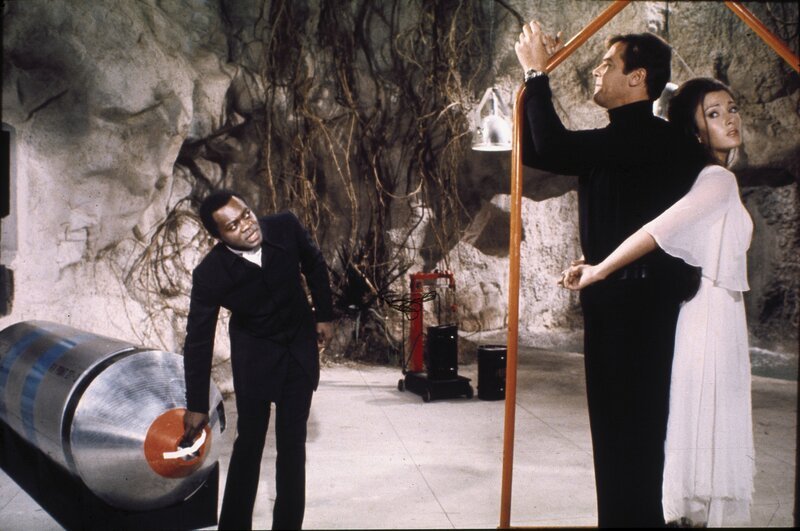 Die Liebenden James Bond (Roger Moore, M.) und Solitaire (Jane Seymour, r.) sind dem machthungrigen Mr. Big (Yaphet Kotto, l.) ausgeliefert. – Bild: ZDF/​George Whitear