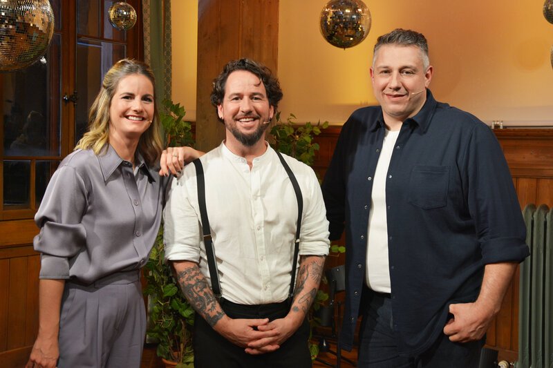 Samschtig-Jass - Musik und Jass mit Alpentainer Trauffer. v.l. Moderatorin Fabienne Gyr, Marc Trauffer und Jass-Schiedsrichter Jörg Abderhalden. – Bild: SRF