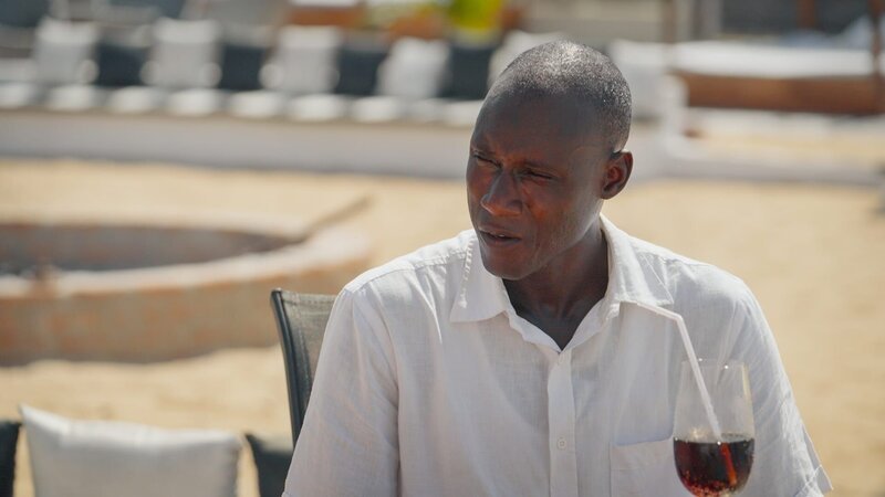 Ebrima talking to Zena on beach – Bild: Warner Bros. Discovery, Inc. or its subsidiaries and affiliates