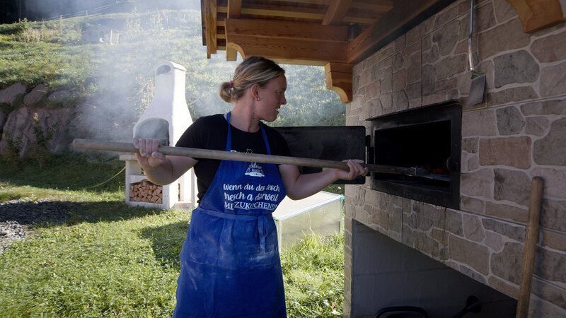 Bergbäuerin Stephanie Schenk am Backofen, wo sie selbst Brote bäckt. – Bild: ORF/​GEOSFILM /​ ZDF und ORF/​GEOSFILM