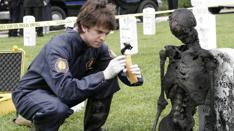 Auf dem Arlington Nationalfriedhof wird eine bis zur Unkenntlichkeit verbrannte Leiche gefunden. Sie liegt direkt auf dem Grab eines Kriegshelden, der im Irak gefallen ist. Zack (Eric Millegan) sucht dort nach Spuren, die die Identität der Leiche klären könnten. – Bild: TVNOW /​ FOX