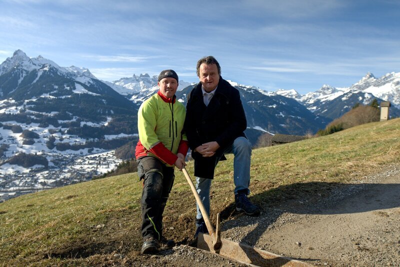 In der idyllischen Gemeinde Bartholomäberg in Vorarlberg gibt es die sogenannten Hand- und Zugdienste. Hanno Settele (r.) trifft Wolfgang Fitsch, der Regenrinnen reinigt und so seinen Gemeindebeitrag leistet. – Bild: Neulandfilm /​ ORF