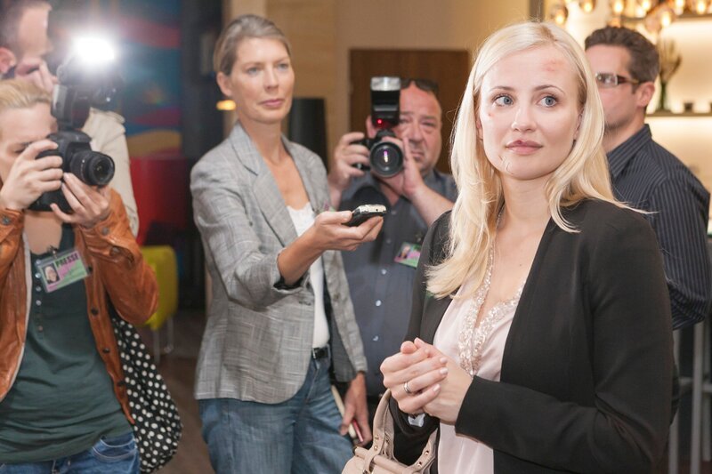 Isabelle (Ania Niedieck, vorne) wird von den Reportern (Komparsen) mit Fragen bombardiert und versucht sich dabei vor Richard in eine gutes Licht zu setzen. – Bild: RTL /​ Kai Schulz, Köln