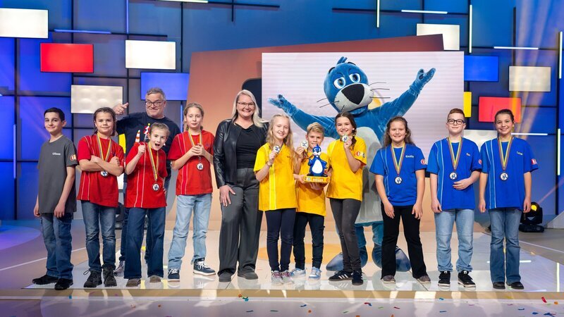Die Rateteams haben heute viel über Bagger, Beton und Co. gelernt. Von links: Kamerakind Ulises, rotes Rateteam mit Elton, Studiogast Sandra Hasenauer, gelbes Rateteam, Piet Flosse und blaues Rateteam – Bild: ZDF und Ralf Wilschewski