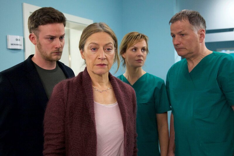 Petra Urbans (Tatjana Blacher, 2. von links) Mann Norbert hatte nach seiner bereits überstandenen OP plötzlich eine schwere Hirnblutung. Ein zweites Mal konnten Dr. Roland Heilmann (Thomas Rühmann, rechts) und Dr. Lea Peters (Anja Nejarri) sein Leben nicht retten. Sie müssen Petra und ihrem Sohn Torben (Till Artur Priebe, links) die Nachricht von Norberts Tod überbringen. – Bild: MDR/​Rudolf K. Wernicke