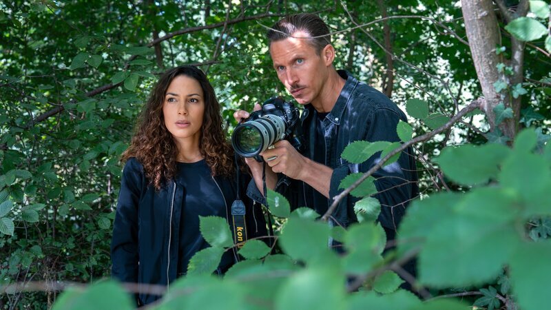 Kim Nowak (Amy Mußul) und Moritz Brenner (Johannes Hendrik Langer) stehen mit einer Kamera im Gebüsch, um einen Verdächtigen zu observieren. – Bild: ZDF und Steffen Junghans