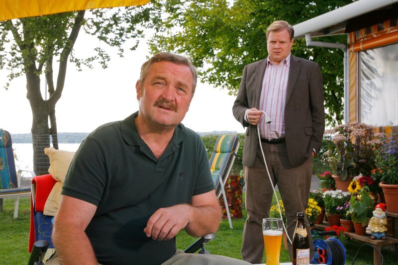 Hat Dauercamper Harald Meierling (Ferry Oellinger, l.) im Streit seinen Wohnwagennachbarn umgebracht? Rosenheim-Cop Hartl (Michael A. Grimm, r.) befragt ihn. – Bild: ZDF/​Bavaria Fernsehprod./​Christian A. Rieger