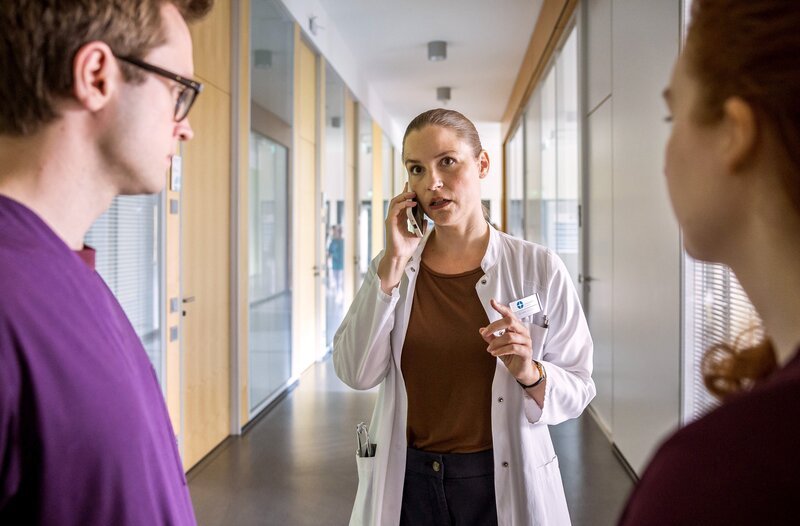 Dr. Julia Berger (Mirka Pigulla, m.) wird über ein Polytrauma in der Notaufnahme des JTK informiert. (v.l.n.r. Olli Porbst (Arne Kertész), Dr. Julia Berger (Mirka Pigulla), Tamar Hummel (Linda Kummer)). – Bild: ARD/​Michael Kremer