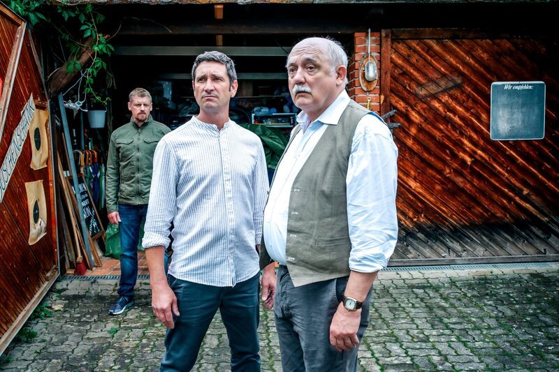 Bezirksinspektor Klaus Lechner (Andreas Kiendl, M.) will zusammen mit Major Max Herzog (Martin Gruber, l.) an der Garage von Erwin Happich (Karl Fischer, r.) herausfinden, was mit seiner alten Freundin Suse wirklich passiert ist. – Bild: ORF/​Satel Film/​Stefan Haring