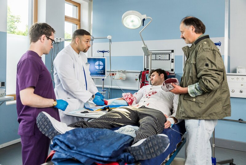 Dr. Matteo Moreau (Mike Adler) und Assistenzarzt Olli Probst (Arne Kertész) machen in der Schockbox eine erste Anamnese mit Patient Raiko Brauer (Oskar Keymer). Der Metzgerlehrling wird von seinem Ausbilder Holger Probst (Cornelius Schwalm) begleitet. (v.l.n.r.: Arne Kertész, Mike Adler, Oskar Keymer, Cornelius Schwalm) – Bild: ARD/​Michael Kremer