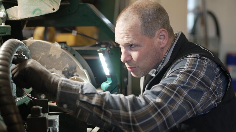 Landmaschinenmechaniker Burkhard Wöltjen tauscht in der Werkstatt an einem Häcksler die Schneidemesser aus. – Bild: NDR /​ video:arthouse /​ Reinhard Bettauer