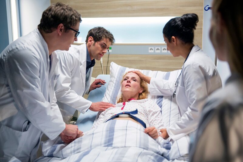 ARD  IN ALLER FREUNDSCHAFT – DIE JUNGEN ÄRZTE, neue Vorabend-Weekly mit 42 Folgen, Folge 1 „Der erste Tag“, am Donnerstag (22.01.15) um 18:50 Uhr im Ersten. Es kommt zu schweren Komplikationen bei der schwangeren Andrea Gerlach (Anja Schiffel, liegend). V.l.n.r.: Elias Bähr (Stefan Ruppe), Dr. Niklas Ahrend (Roy Peter Link), Dr. Leyla Sherbaz (Sanam Afrashteh) und Julia Berger (Mirka Pigulla) kümmern sich um sie. – Bild: ARD/​Tom Schulze