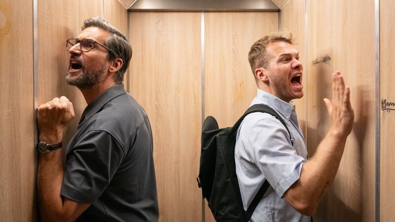 Guideon (Tom Beck, l.) und Julian Beil (Ben Münchow, r.) gefangen im Aufzug: Während der Zwangspause brechen alte Konflikte und neue Absurditäten hervor. – Bild: ZDF und Michael Kötschau