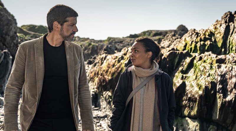 Die Witwe Romy (Sithembile Menck, re.) berichtet Kommissar Dupin (Pasquale Aleardi, li.) von ihren privaten Nachforschungen auf der Insel. – Bild: ARD Degeto Film/​filmpool fiction/​Wolfgang Ennenbach