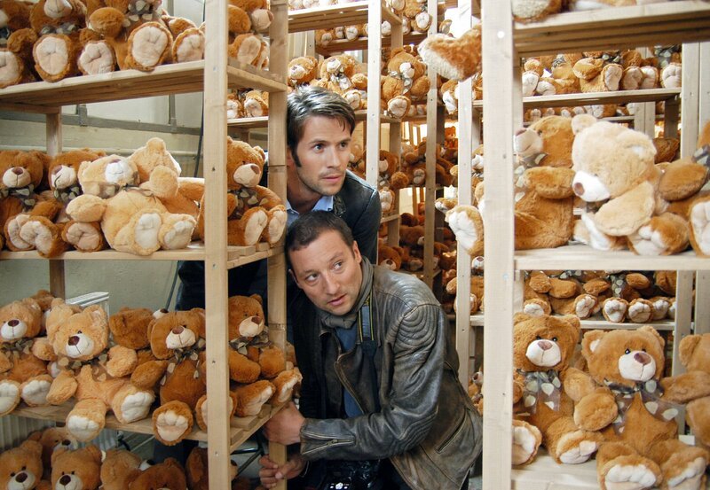 Die Reporter Nico (Christian Oliver, oben) und Olaf (Oliver Broumis) auf Recherche in der Spielzeugfabrik. – Bild: ARD Degeto/​Hans-Joachim Pfeiffer