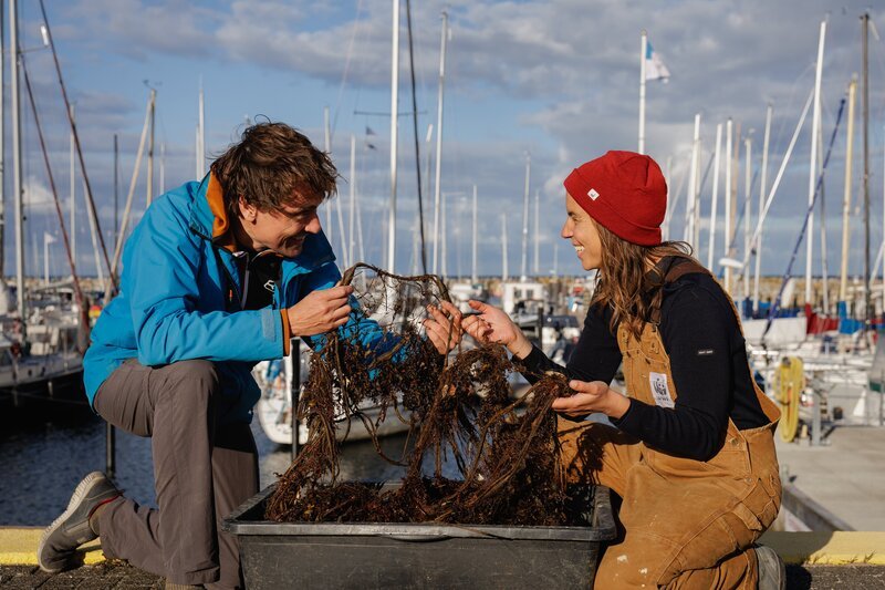 Uli Kunz und WWF-Mitarbeiterin Gabrielle Dederer sitzen am Olympiahafen in Schilksee. Sie haben ein Geisternetz in der Hand, welches sie aus der Ostsee geholt haben. – Bild: ZDF und Niklas Ruddies