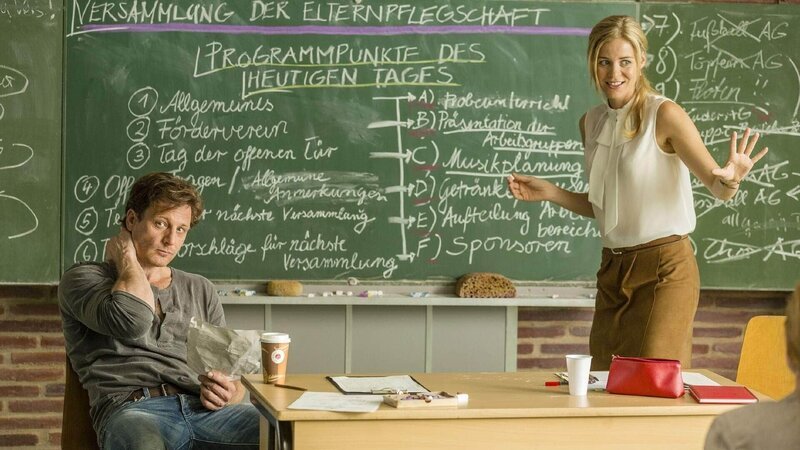 Stefan (Hendrik Duryn) und Karin (Jessica Ginkel) bei der Elternversammlung. Während Karin von Arbeitsteilung spricht interessiert sich Stefan mehr für Nina. – Bild: TVNOW /​ Frank Dicks