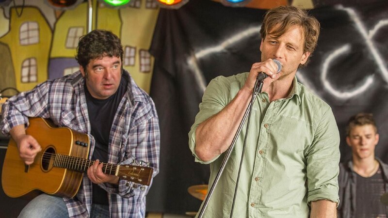 Stefan (Hendrik Duryn, r.) lässt sich von Sievers (Rainer Piewek) auf der Gitarre begleiten und gibt den Liebessong als seinen aus. – Bild: TVNOW