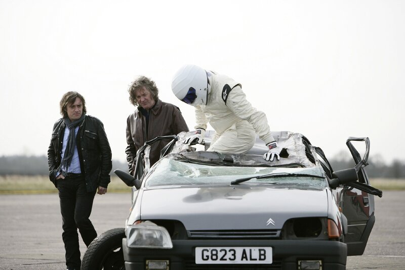 Stig klettert aus dem kaputten Citroen AX GT nach misslungener Sicherheits-Challenge auf dem Prodrive Test Track. Hinten: Richard Hammond (l.), James May. – Bild: RTL /​ © BBC Worldwide