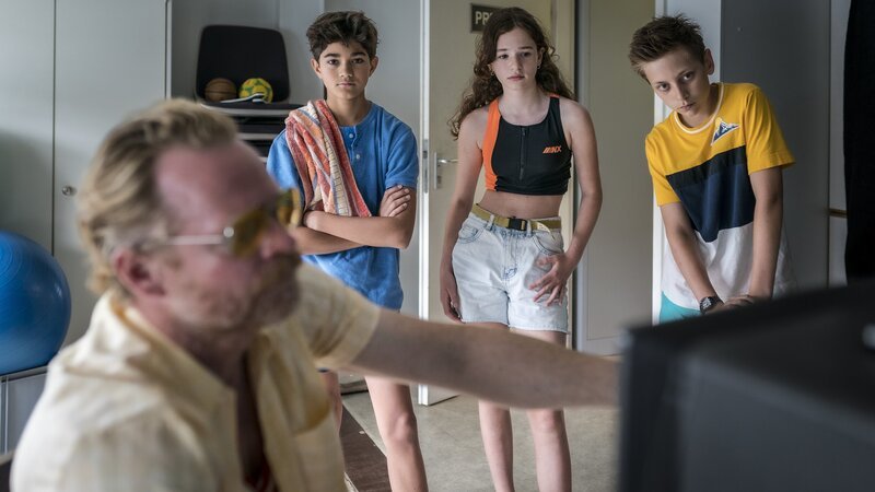 Hakim, Leo und Moritz werfen gemeinsam mit Bademeister Theo einen Blick auf die Überwachungskamera. – Bild: NDR/​Boris Laewen