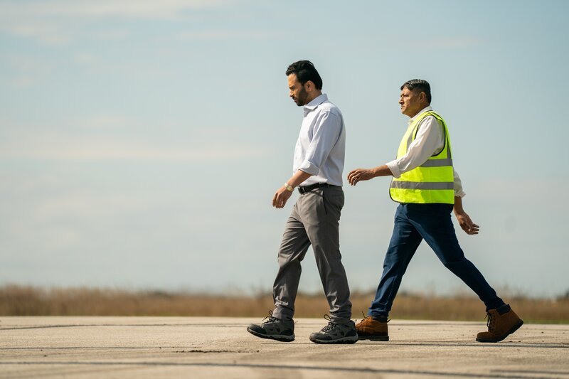 Der zweite Ermittler (gespielt von Manny Thind) inspiziert das Ende der Landebahn am Calicut International Airport, untersucht die Tischkonfiguration und bewertet das Geländeprofil, wo der Air India Express Flug 1344 auseinanderbrach, nachdem er die verfügbare Landestrecke überschritten hatte. (Cineflix 2025/​Shay Markowitz) – Bild: Shay Markowitz /​ Cineflix