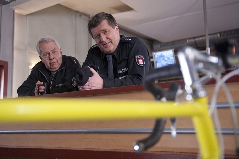 Hans (Bruno F. Apitz, r) ganzer Stolz ist sein neues Rennrad. Wolle (Harald Maack, l) glaubt nicht ganz an die neue Sportlichkeit seines Kollegen. – Bild: ZDF