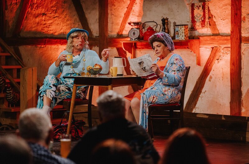 v.r.n.l.: Jetzt reichts: Rita (Hillu Stoll, rechts) will sich aus den Zwängen des Ehemannes befreien und sucht einen Job. Nachbarin Gisela (Franz Auber) will ihr das ausreden. – Bild: SWR/​Ronny Zimmermann