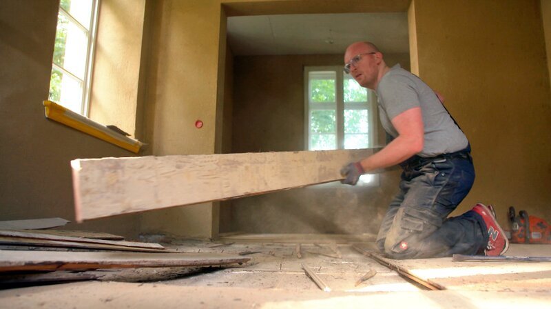 Bauherr Daniel Hoherz beim Entfernen der alten Dielen im Wohnzimmer der Alten Apotheke in Nusse. – Bild: NDR/​Ulrike Schede