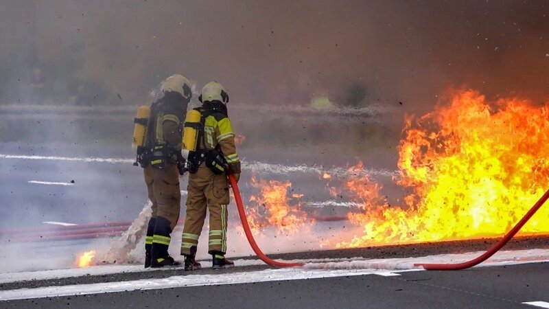 Two firefighters extinguish a burning truck in Dresden. – Bild: Warner Bros. Discovery