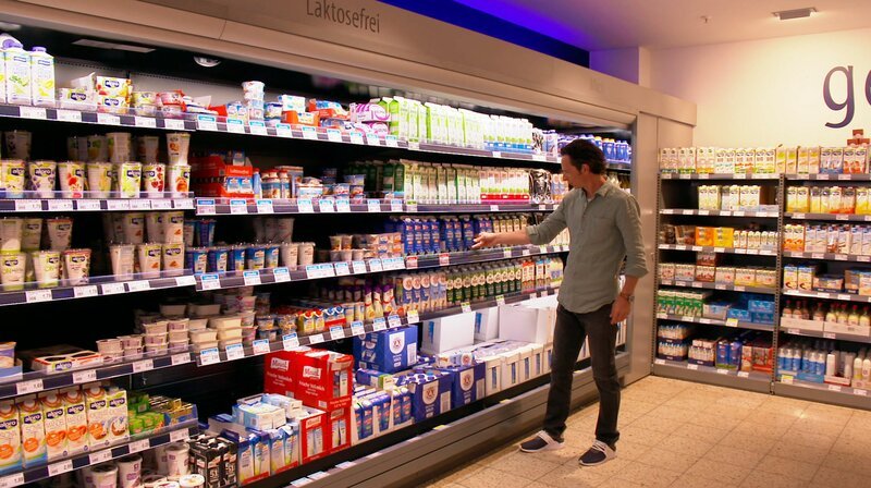Jo Hiller vor dem Milchregal: Große Auswahl, viele Sorten – ein Überblick über die Vielfalt der Milchprodukte im Supermarkt. – Bild: NDR/​Manuela Rose
