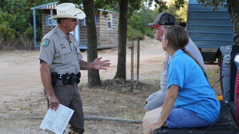 Fish and Game Officer Jake Brown speaking to a couple on the farm. – Bild: Discovery Communications, LLC