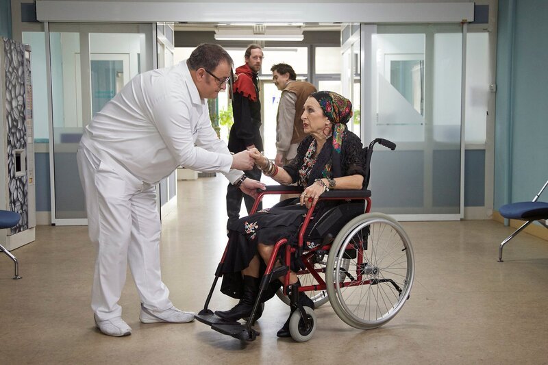 Hans-Peter Brenner (Michael Trischan, links) traut seinen Augen nicht, als ein Henker und ein Buckliger (Komparsen, hinten) eine Wahrsagerin in die Klinik bringen. Erika Schultheiß, alias Frau Rosita, (Daniela Ziegler, rechts) ist beim Handlesen zusammengebrochen. – Bild: MDR/​Rudolf Wernicke