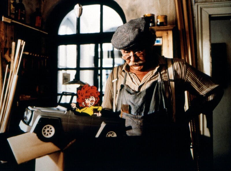 Pumuckl freut sich über das Spielzeugauto, das Meister Eder (Gustl Bayrhammer) ihm geschenkt hat. – Bild: BR/​Infafilm