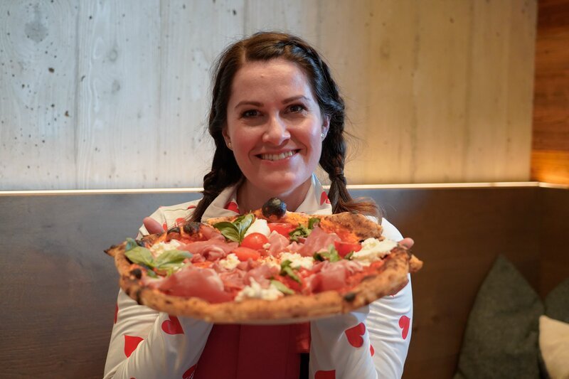 Heimatleuchten Moderatorin Conny Bürgler mit Pizza auf der Hütte „Deantnerin“. – Bild: Lena Moik /​ ServusTV /​ Degn Film